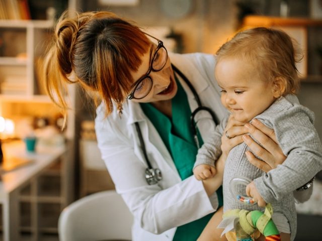 Female doctor playing with baby boy on the table in doctors office